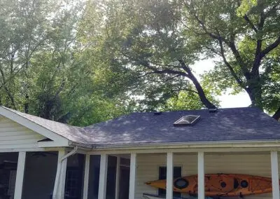 Dark shingles around a skylight on a roof, with a porch below